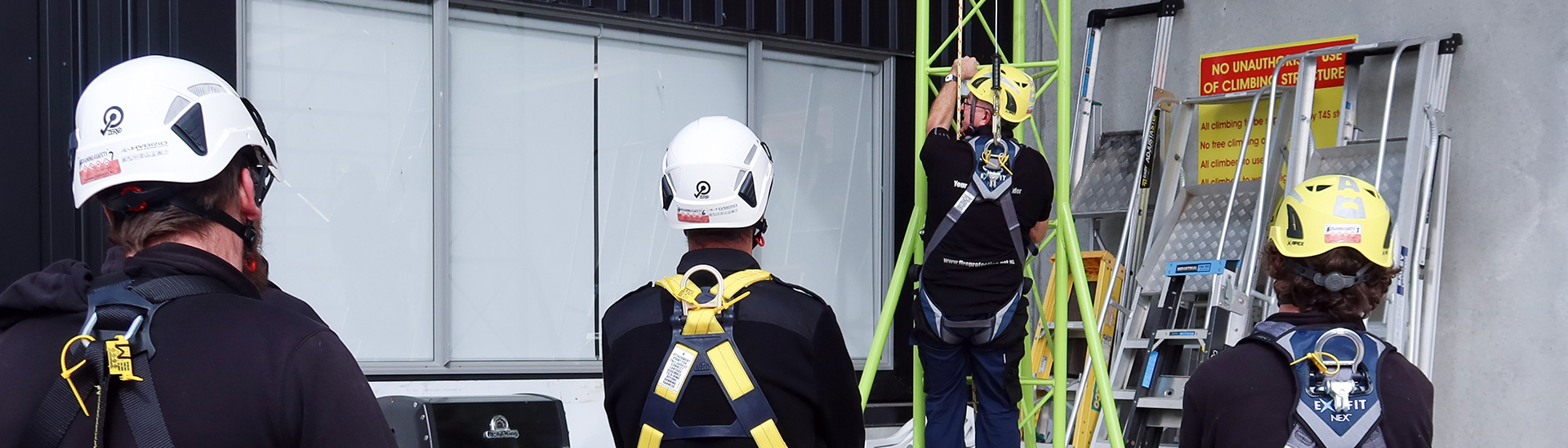 A trainer showing three trainees how to safely climb scaffolding during Heights Training